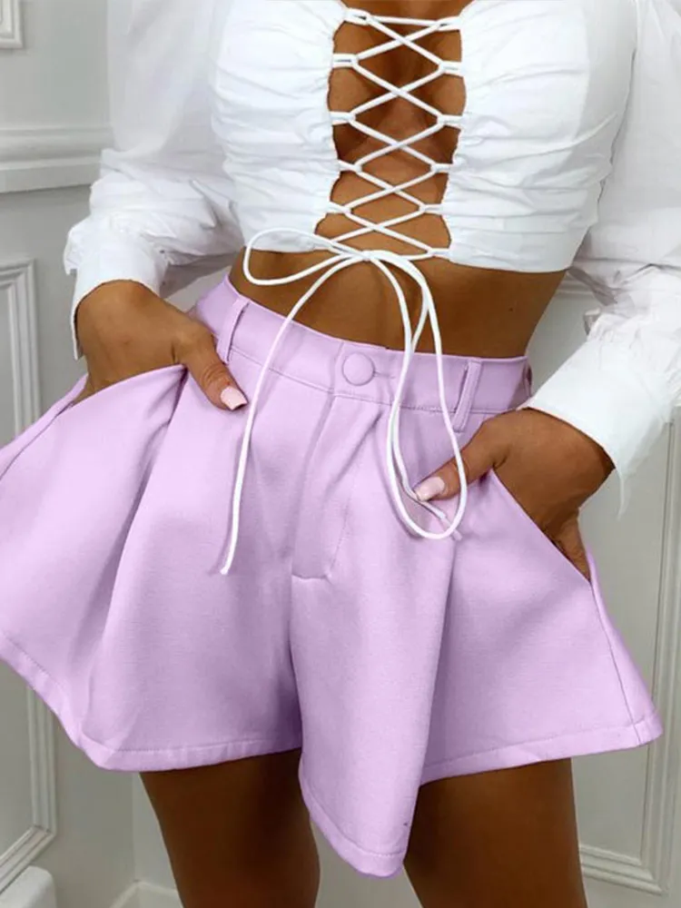 Close front view of light purple high-waisted ruffle shorts with a model’s hands in the side pockets.
