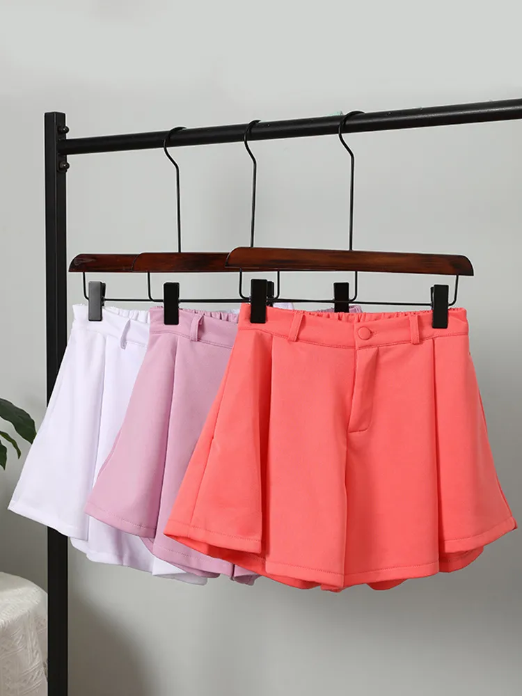 White, light purple and coral-pink high-waisted ruffle shorts displayed together on hangers.