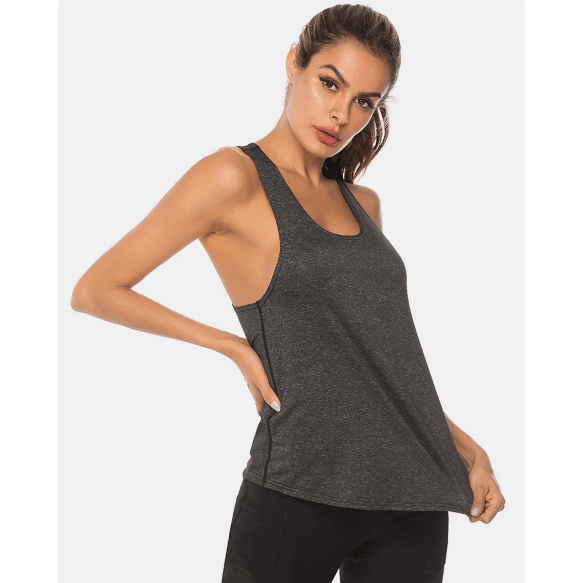 Model holding the hem of a charcoal long scoop-neck workout tank top.