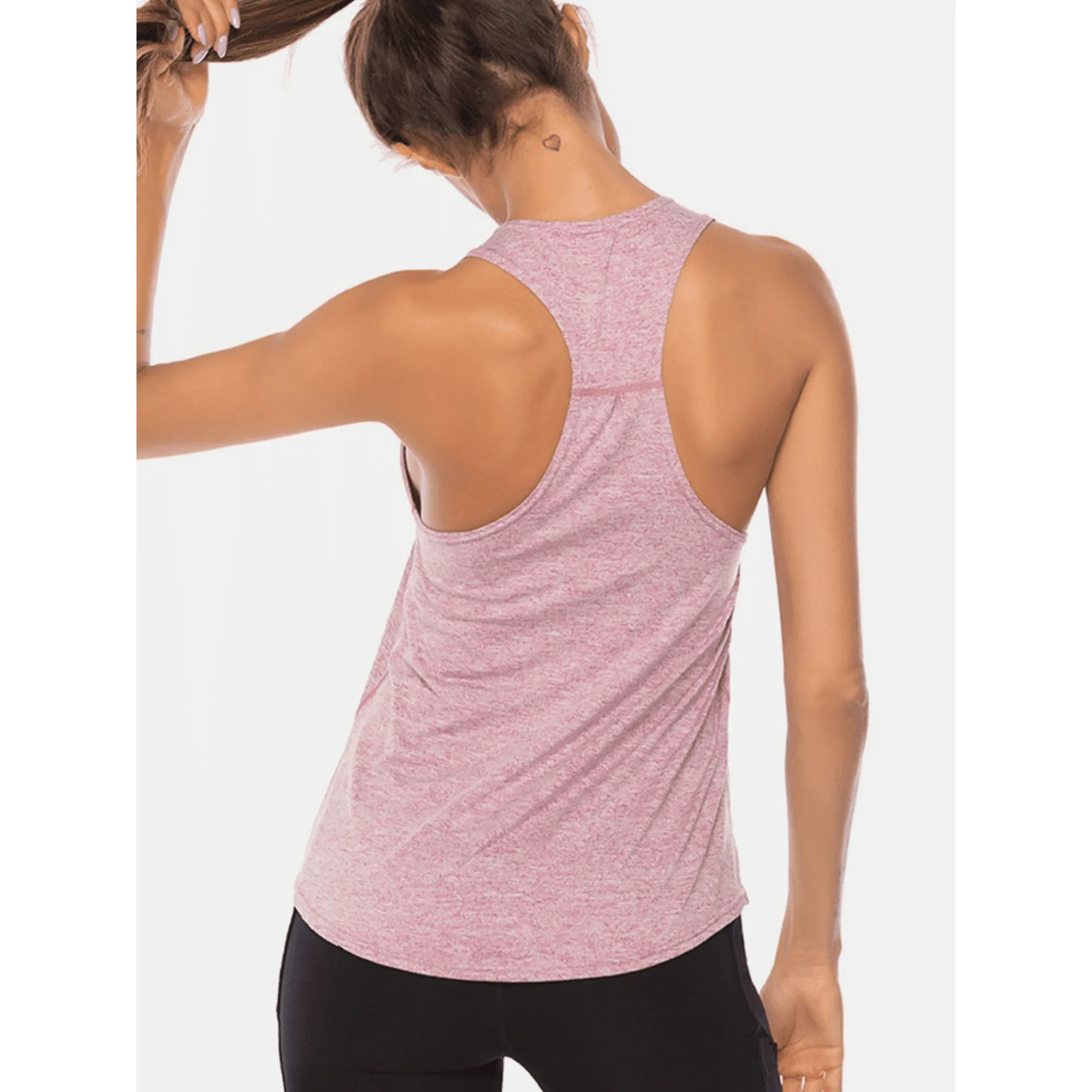 Model posing from behind in a light pink racerback workout tank top.